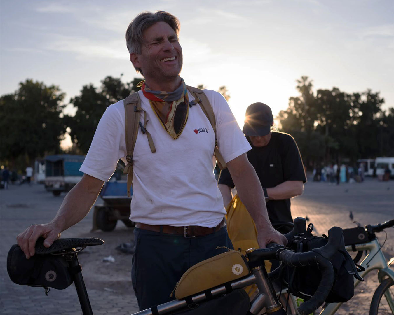 Man som står vid sin cykel och har på sig en vit T-shirt från Fjällrävens kollektion Hoja